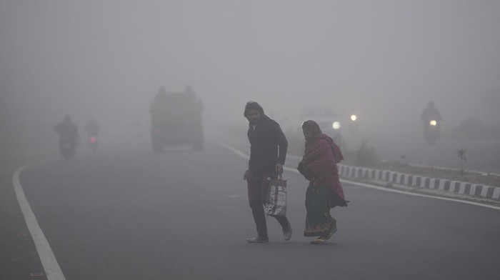 Commuters drive through a street enveloped by dense fog on the outskirts of Jammu, India, Monday, Dec. 30, 2024 .(AP Photo/Channi Anand)