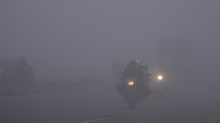 Commuters drive through a street enveloped by dense fog on the outskirts of Jammu, India, Monday, Dec. 30, 2024 .(AP Photo/Channi Anand)