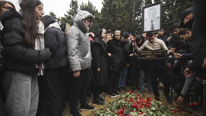 People stand at the grave of pilot in command Igor Kshnyakin during a funeral of the crew members of the Azerbaijan Airlines Embraer 190 killed in a deadly plane crash in Kazakhstan this week, at the II Alley of Honor in Baku, Azerbaijan, Sunday, Dec. 29, 2024. (AP photo)