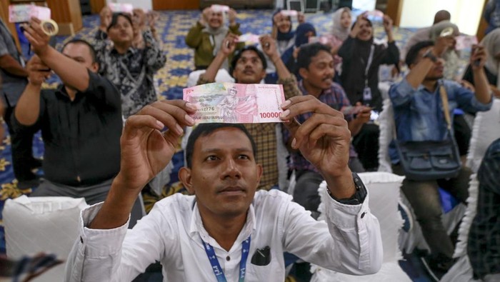 Seorang jurnalis mengamati uang rupiah pecahan 100 ribu menggunakan alat kaca pembesar saat mengikuti sosialisasi keaslian uang rupiah di Ternate, Maluku Utara, Selasa (31/12/2024). Kantor Perwakilan Bank Indonesia Provinsi Maluku Utara terus memberikan sosialisasi mengenai keaslian uang rupiah sebagai upaya memperkenalkan karakteristik uang rupiah asli kepada jurnalis untuk mencegah penyebaran uang palsu yang dapat mempengaruhi stabilitas ekonomi.