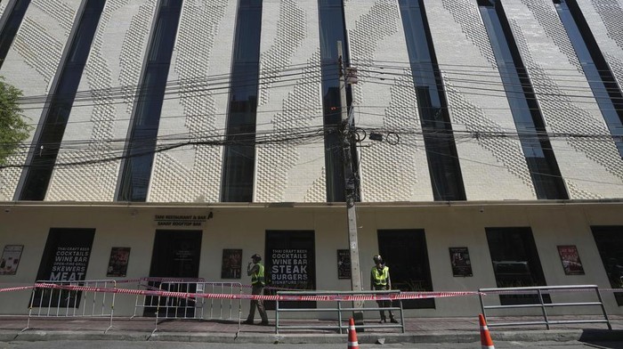 Policemen stand guard after a hotel fire in Bangkok, Thailand, Monday, Dec. 30, 2024. (AP Photo/Sakchai Lalit)