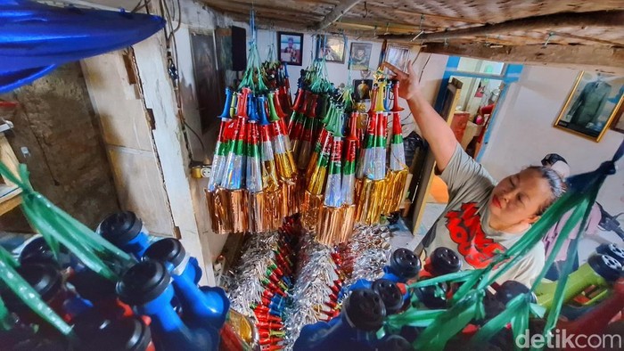 Marini (40), tengah memproduksi terompet bong di Kampung Stasion Utara, Desa Banjaran, Kecamatan Banjaran, Senin (30/12/2024).