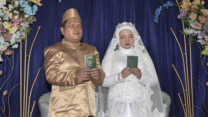 Nikah Massal Tuna Netra se-Priangan Timur Pasangan pengantin tuna netra menunjukan buku nikah saat berlangsungnya nikah massal tuna netra se-Priangan Timur di Gedung Aisyah, Kota Tasikmalaya, Jawa Barat, Selasa (31/12/2024). Pernikahan massal gratis yang diikuti lima pasangan pengantin tuna netra itu untuk membantu para penyandang disabilitas yang tidak mampu secara ekonomi dalam mendapatkan legalitas secara hukum negara.