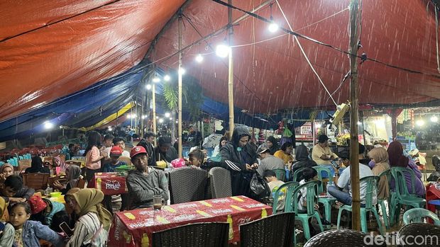 Pengunjung berteduh lantaran Anjungan Pantai Losari Makassar diguyur hujan lebat jelang pergantian tahun baru 2025. Yaslinda Utari Kasim/detikSulsel