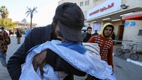 Jumaa Al-Batran meninggal karena hipotermia setelah tinggal di tenda bersama keluarganya di pengungsian di Deir Al-Balah di Jalur Gaza bagian tengah, pada 29 Desember 2024. Yahya Al-Batran, ayah dari Jumaa Al-Batran sedih ketika menggendong jenazah anaknya. (Foto: REUTERS/Ramadan Abed)