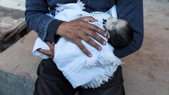 People pray next to the bodies of two Palestinian babies, including infant Jumaa Al-Batran, who died of hypothermia after living in a tent with his displaced family, at Al-Aqsa Martyrs Hospital in Deir Al-Balah in the central Gaza Strip, December 29, 2024. REUTERS/Ramadan Abed