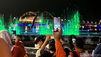 Warga nampak mengabadikan dengan mengunakan ponsel mereka saat pertunjukan show laser air mancur menari di Jembatan Suroboyo.