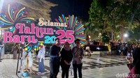 Sejumlah warga berfoto dengan latar belakang hiasan lampu tahun baru 2025 di halaman Balai Kota Surabaya.