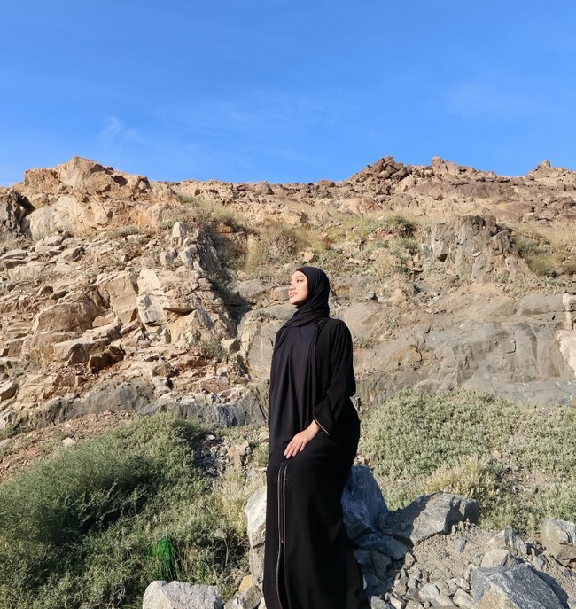 Pelantun lagu Pemilik Rindu ini juga mengunggah kita sedang menikmati pemandangan alam selama di Tanah Suci. Dalam foto ini, Naura terlihat simpel dan anggun mengenakan hijab pashmina dan dress hitam.  Foto: Dok. Instagram @naura.ayu.