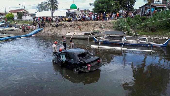 Foto udara sejumlah warga menyaksikan proses evakuasi mobil yang terjun ke sungai di Jembatan Megawati, Manado, Sulawesi Utara, Kamis (2/1/2025). Kecelakaan yang disebabkan kelalaian pengemudi tersebut mengakibatkan mobil terperosok ke sungai dan tidak ada korban jiwa.