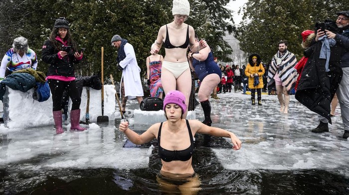 Brrr.. Warga Kanada Awali Tahun dengan Berendam di Danau Es Canda-Leigh Habonimana dips in the waters of Gatineau Park's Meech Lake in Chelsea, Que., during a polar bear dip on New Year's Day, Wednesday, Jan. 1, 2025. (Justin Tang /The Canadian Press via AP)