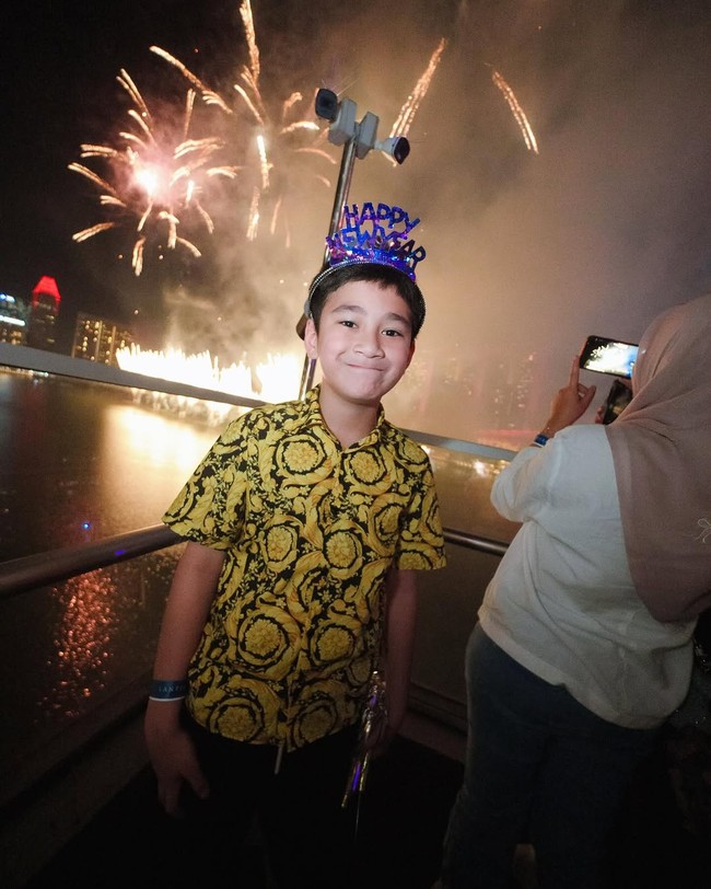 Raffi dan Nagita sempat membagikan momen kebersamaan mereka melalui unggahan di media sosial. Dalam foto-foto yang diunggah, keluarga ini terlihat menikmati suasana malam Singapura yang gemerlap, dengan latar belakang ikon Marina Bay Sands dan pertunjukan kembang api spektakuler. (Foto: Instagram/@raffinagita1717)