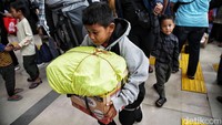 Tampak seorang penumpang anak ikut membawa barang yang dibungkus kardus dan plastik.