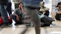 Sebagian penumpang menunggu jadwal keberangkatan dengan duduk-duduk di lantai stasiun.