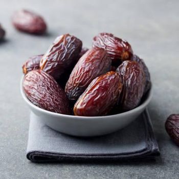 Fresh medjool dates in bowl. Grey background. Copy space