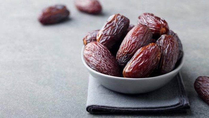 Fresh medjool dates in bowl. Grey background. Copy space