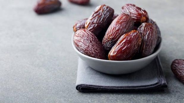 Fresh medjool dates in bowl. Grey background. Copy space