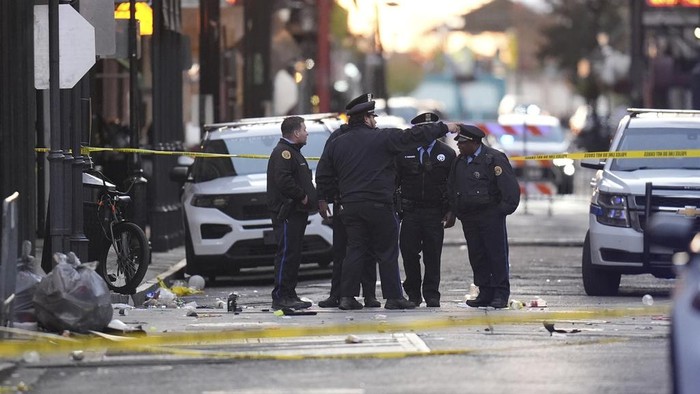 A black flag with white lettering lies on the ground rolled up behind a pickup truck that a man drove into a crowd on Bourbon Street in New Orleans, killing and injuring a number of people, early Wednesday morning, Jan. 1, 2025. The FBI said they recovered an Islamic State group flag, which is black with white lettering, from the vehicle. (AP Photo/Gerald Herbert)