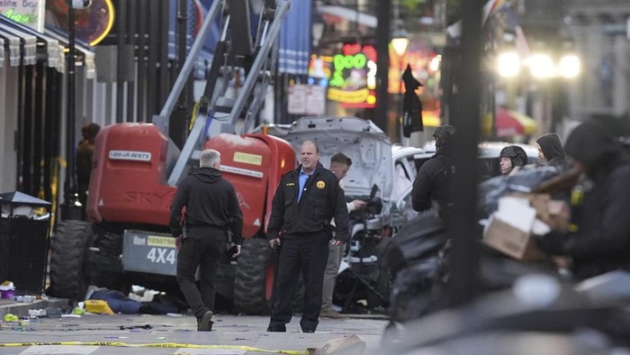 A black flag with white lettering lies on the ground rolled up behind a pickup truck that a man drove into a crowd on Bourbon Street in New Orleans, killing and injuring a number of people, early Wednesday morning, Jan. 1, 2025. The FBI said they recovered an Islamic State group flag, which is black with white lettering, from the vehicle. (AP Photo/Gerald Herbert)