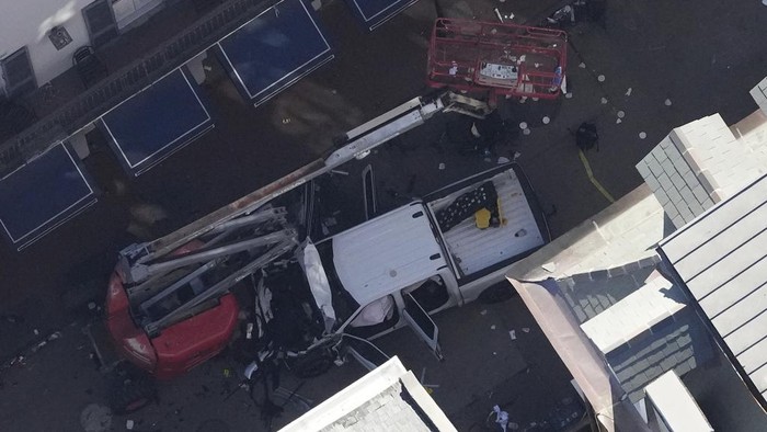 A black flag with white lettering lies on the ground rolled up behind a pickup truck that a man drove into a crowd on Bourbon Street in New Orleans, killing and injuring a number of people, early Wednesday morning, Jan. 1, 2025. The FBI said they recovered an Islamic State group flag, which is black with white lettering, from the vehicle. (AP Photo/Gerald Herbert)
