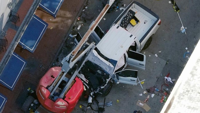 A black flag with white lettering lies on the ground rolled up behind a pickup truck that a man drove into a crowd on Bourbon Street in New Orleans, killing and injuring a number of people, early Wednesday morning, Jan. 1, 2025. The FBI said they recovered an Islamic State group flag, which is black with white lettering, from the vehicle. (AP Photo/Gerald Herbert)