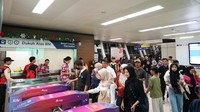 Para penumpang antre melakukan tap menggunakan uang elektronik di stasiun LRT Jabodebek.