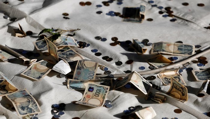 A man throws a banknote before praying on the first day of the new year at the Meiji Shrine in Tokyo, Japan January 1, 2025. REUTERS/Kim Kyung-Hoon