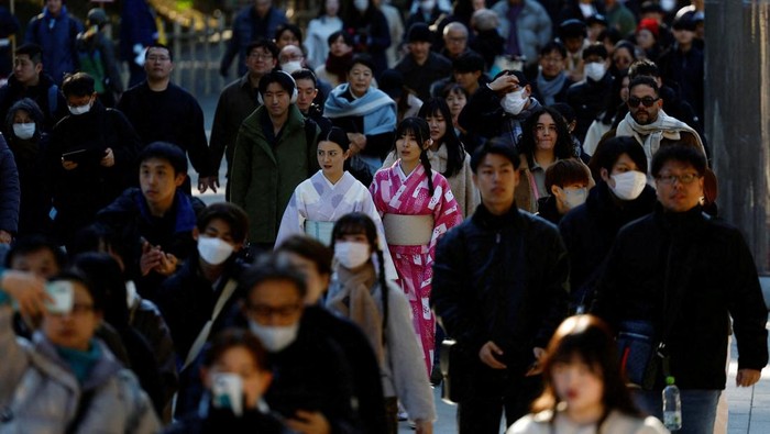 A man throws a banknote before praying on the first day of the new year at the Meiji Shrine in Tokyo, Japan January 1, 2025. REUTERS/Kim Kyung-Hoon