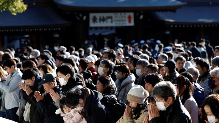 A man throws a banknote before praying on the first day of the new year at the Meiji Shrine in Tokyo, Japan January 1, 2025. REUTERS/Kim Kyung-Hoon