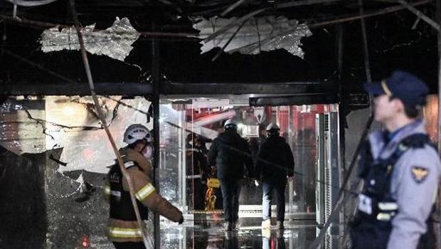 Investigators and firefighters are seen at the entrance of a damaged commercial building in the aftermath of a fire that broke out at the Bundang district in Seongnam on January 3, 2025. (Photo by Philip FONG / AFP)