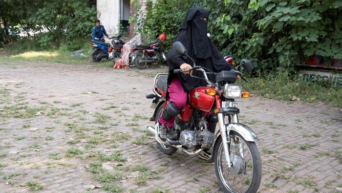 Perempuan Bersepeda Motor Makin Populer di Pakistan gegara Mobil Mahal Humaira Rafaqat, a senior traffic warden, teaches women how to ride a bike while wearing an abaya, during a training session as part of the