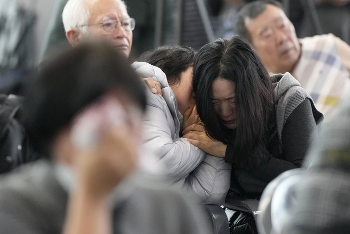 Relatives of passengers on a plane which skidded off a runway and burst into flames, react at Muan International Airport in Muan, South Korea, Monday, Dec. 30, 2024. (AP Photo/Ahn Young-joon)