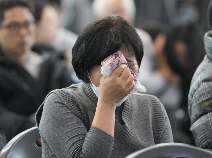 A relative of a passenger of a plane which burst into flames reacts at a temporary shelter at Muan International Airport in Muan, South Korea, Monday, Dec. 30, 2024. (AP Photo/Ahn Young-joon)