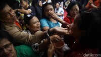 Para peserta saling mengoleskan bedak ke wajah dalam acara budaya Mandi Mandi Kampung Tugu di Cilincing, Jakarta Utara, Minggu (5/1/2025).