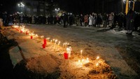 Orang-orang menyalakan lilin pada Minggu di depan sebuah gereja di Cetinje yang dekat dengan tempat penembakan dimulai dan berdiri dalam keheningan selama 12 menit untuk menghormati para korban.  