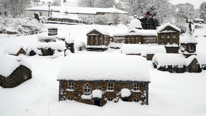 Inggris Memutih Dilanda Badai Salju Lowson Robinson is pictured in the heavy snow with his scaled miniature famous landmarks which are located in his garden in Nenthead, England, as the severe weather continues across England, Sunday, Jan. 5, 2025. (AP Photo/Scott Heppell)