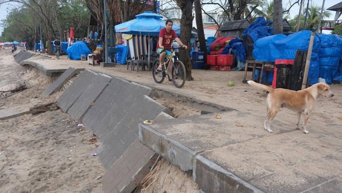 Wisatawan mancanegara berjalan di area pedestrian yang rusak akibat hempasan ombak di Pantai Kuta, Badung, Bali, Senin (6/1/2025). Pedestrian yang digunakan sebagai akses olahraga bagi wisatawan tersebut mengalami kerusakan sepanjang 20 meter akibat gelombang tinggi yang terjadi pada Sabtu (4/1). ANTARA FOTO/Nyoman Hendra Wibowo/foc.
