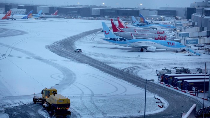 Staff use tractors to help clear snow from around aircraft after overnight snowfall caused the temporary closure of Manchester Airport in Manchester, Britain, January 5, 2025. REUTERS/Phil Noble