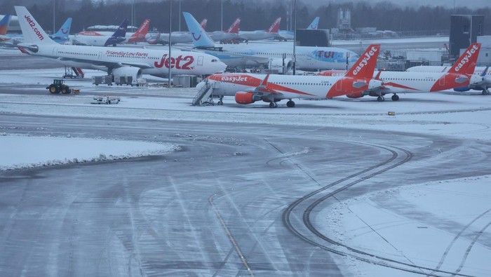 Penampakan Salju Tebal Selimuti Bandara Manchester Staff use tractors to help clear snow from around aircraft after overnight snowfall caused the temporary closure of Manchester Airport in Manchester, Britain, January 5, 2025. REUTERS/Phil Noble