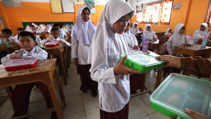 Pelajar menerima paket makanan pada pelaksanaan program Makan Bergizi Gratis (MBG) hari pertama di SD Negeri 56 Banda Aceh, Aceh, Senin (6/1/2025). Program MBG untuk pelajar tingkat TK, SD, SMP dan SMA pada hari pertama dilaksanakan serentak di enam kabupaten/kota untuk dilakukan evaluasi sebelum didistribusikan ke seluruh sekolah yang tersebar di provinsi Aceh. ANTARA FOTO / Irwansyah Putra/nz.