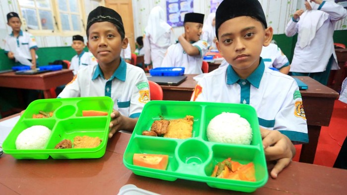 Pelajar menerima paket makanan pada pelaksanaan program Makan Bergizi Gratis (MBG) hari pertama di SD Negeri 56 Banda Aceh, Aceh, Senin (6/1/2025). Program MBG untuk pelajar tingkat TK, SD, SMP dan SMA pada hari pertama dilaksanakan serentak di enam kabupaten/kota untuk dilakukan evaluasi sebelum didistribusikan ke seluruh sekolah yang tersebar di provinsi Aceh. ANTARA FOTO / Irwansyah Putra/nz.