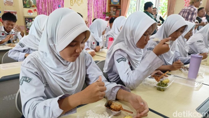 Siswa di SMP Negeri 19 Palembang menikmati makanan gratis di Palembang.