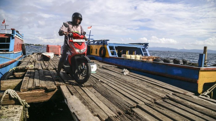 Pengendara sepeda motor melintas di atas dermaga yang rusak di Kelurahan Gamalama Ternate, Maluku Utara, Senin (6/1/2025).Dermaga yang dijadikan sebagai tambatan perahu bagi nelayan tersebut rusak dan sebagian besar papan telah lepas yang menyisakan hanya rangka kayu dan kini belum dilakukan perbaikan oleh pemerintah setempat. ANTARA FOTO/Andri Saputra/nz.