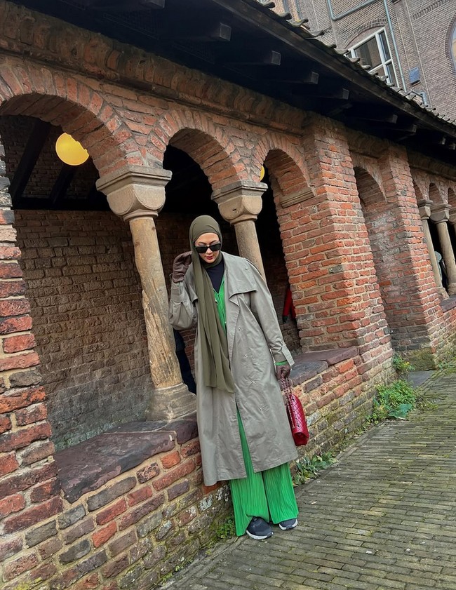 Memakai busana layering, penampilan Paula tetap minimalis dan stylish. Lapisan pertama Paula memakai inner hitam, kemudian ia memakai jumpsuit plisket hijau muda. Lalu ia padukan dengan long coat hijau army. Foto: Dok. Instgram @paula_verhoeven.