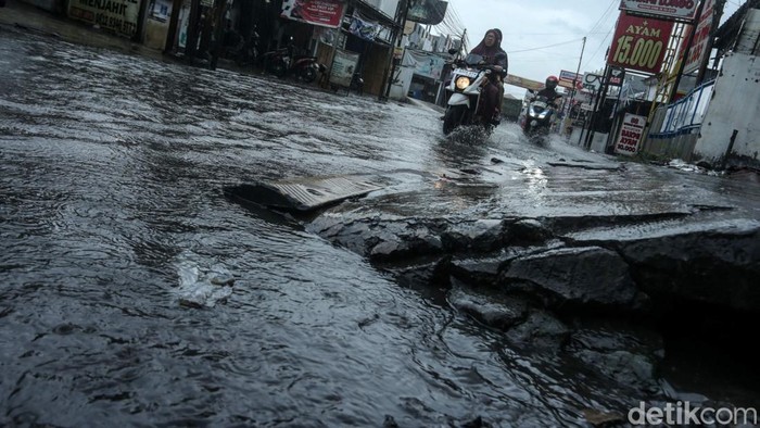 Hujan mengguyur kawasan Tambun, Bekasi. Selokan jalan yang mampet membuat jalanan tergenang. Seperti yang terlihat di Jalan Mekarsari Tengah, Selasa (7/1/2025).