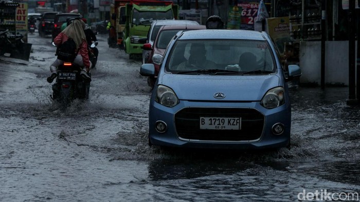 Hujan mengguyur kawasan Tambun, Bekasi. Selokan jalan yang mampet membuat jalanan tergenang. Seperti yang terlihat di Jalan Mekarsari Tengah, Selasa (7/1/2025).