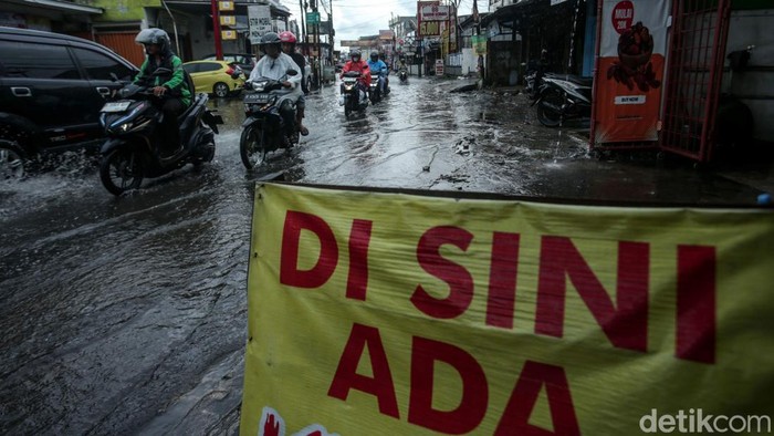Hujan mengguyur kawasan Tambun, Bekasi. Selokan jalan yang mampet membuat jalanan tergenang. Seperti yang terlihat di Jalan Mekarsari Tengah, Selasa (7/1/2025).