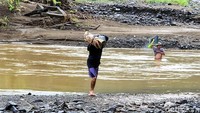 Mereka terlihat mengangkat kayu hingga sejumlah barang saat menyebrangi arus sungai (Foto: Syahdan Alamsyah/detikJabar).