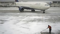 Seorang pekerja membersihkan salju dari landasan sebelum mengarahkan pesawat Delta Air Lines di Bandara Wayne County, Detroit Metropolitan, di Romulus, Michigan, Senin (6/1/2025). Situs FlightAware.com mencatat, total pembatalan penerbangan dalam, menuju, atau keluar dari AS hari ini sebanyak 1.446. Selain itu, lebih dari 870 penerbangan dilaporkan ditunda. Di wilayah Washington, D.C., lebih dari 780 penerbangan dibatalkan. AP/Charlie Riedel
