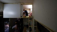 Para penghuni tinggal di tempat tidur susun kayu lapis yang dibuat khusus, masing-masing memiliki pintu geser.  